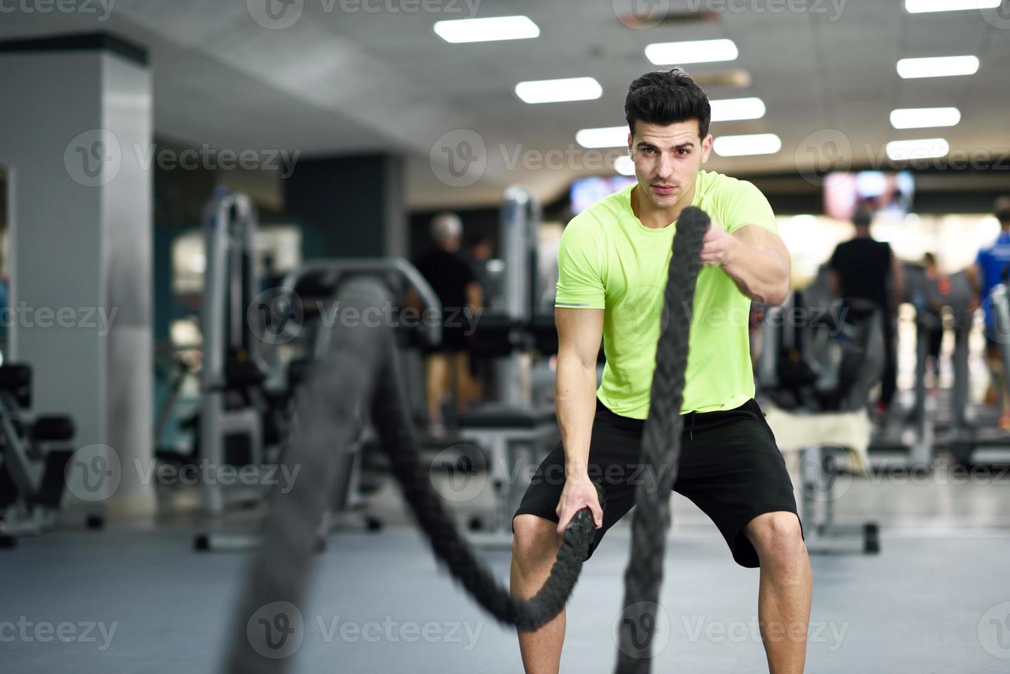 homme avec des cordes de combat s'exerce dans la salle de fitness. photo