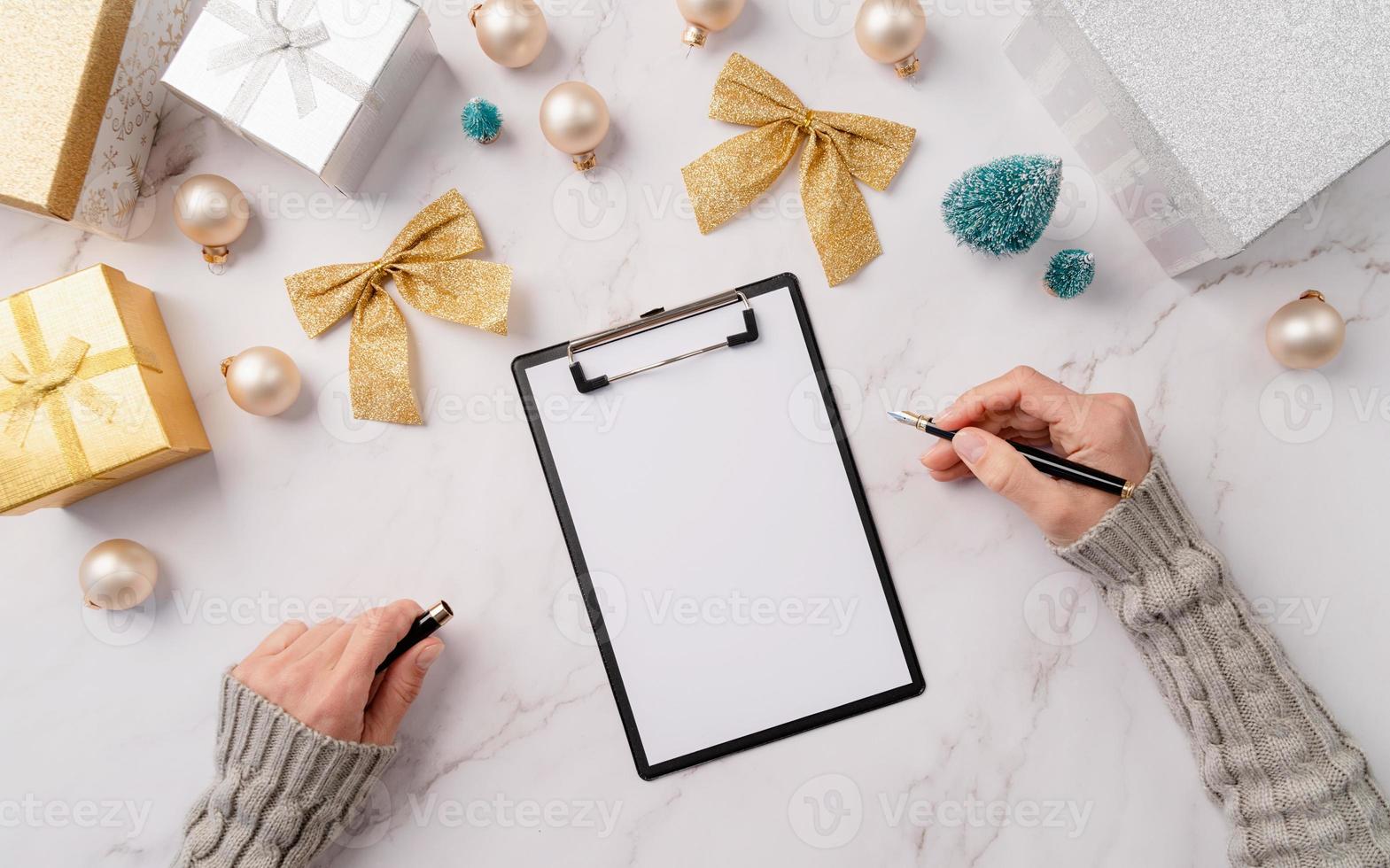 vue de dessus les mains écrivant les objectifs du nouvel an, la résolution ou la liste de courses sur un papier vierge. conception de maquette photo
