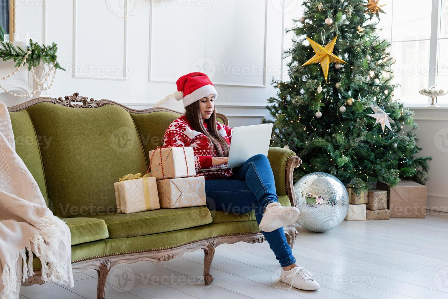 Jeune femme assise sur un canapé dans un salon décoré travaillant sur un ordinateur portable photo