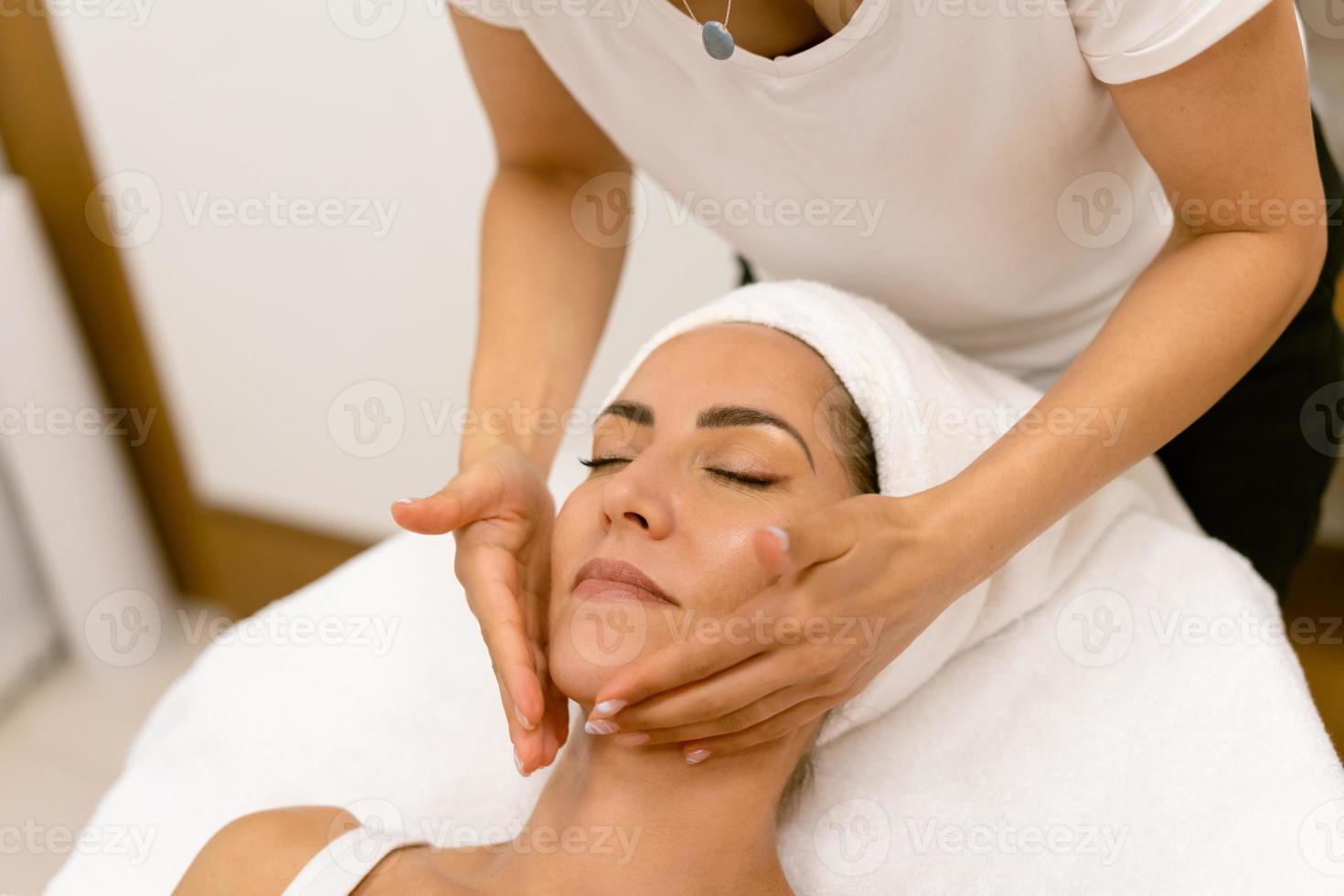 femme d'âge moyen ayant un massage de la tête dans un salon de beauté. photo