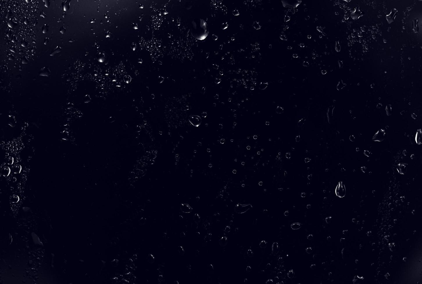 gouttes d'eau sur fond noir. gouttelettes d'eau de rosée abstraites sur une vitre pour un effet de superposition de photos ou pour donner un effet frais sur la maquette de boissons. plan macro sur la goutte de pluie détaillée.