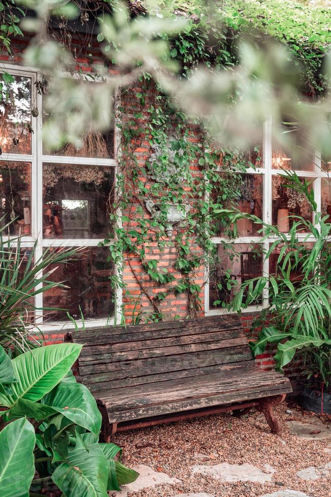 Banc en bois par maison en brique dans un jardin tropical photo