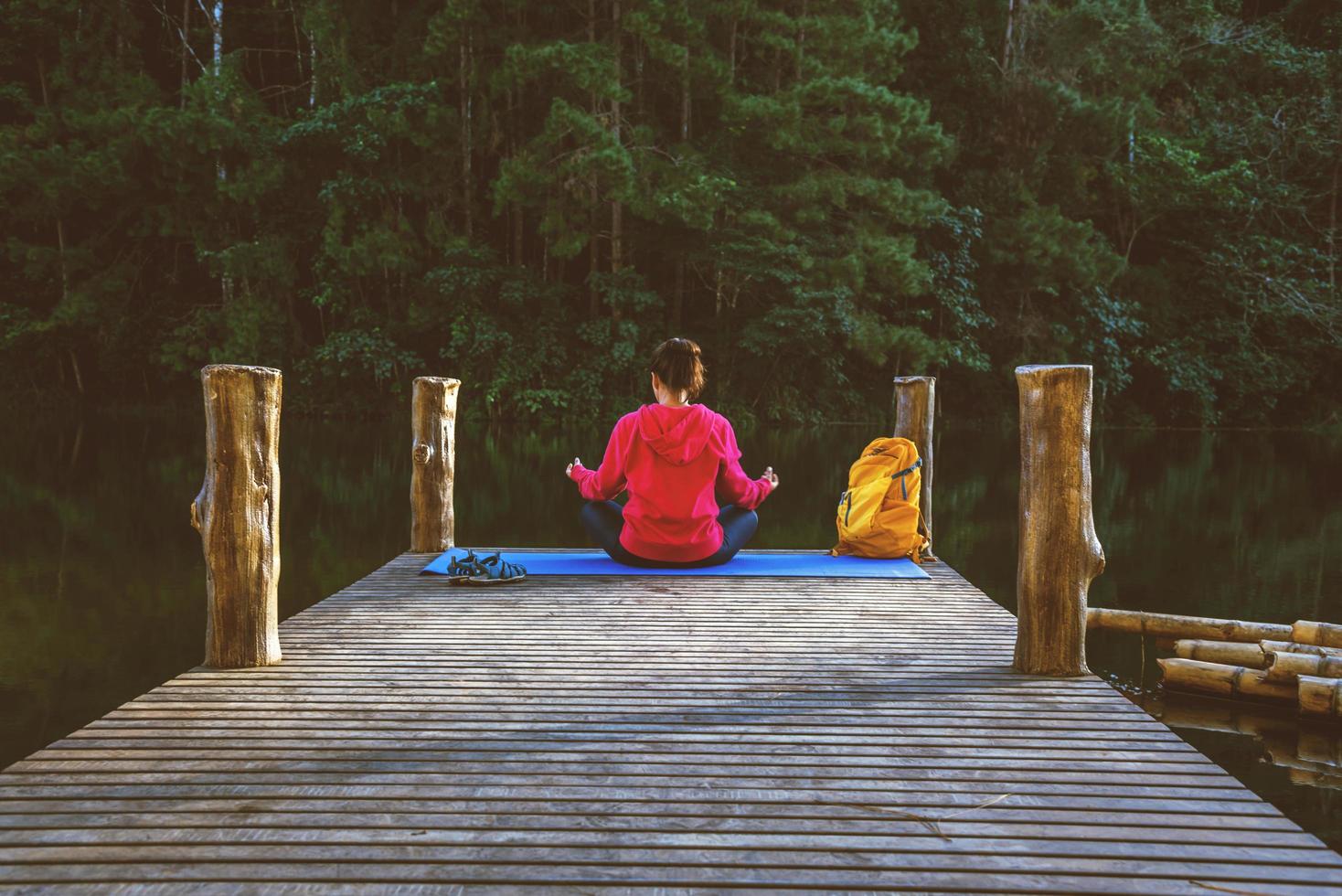 les femmes asiatiques se détendent pendant les vacances. jouer si yoga. sur la montagne, faire de l'exercice, jouer au yoga sur le pont de bambou au bord du lac dans la brume à pang ung, en thaïlande. photo