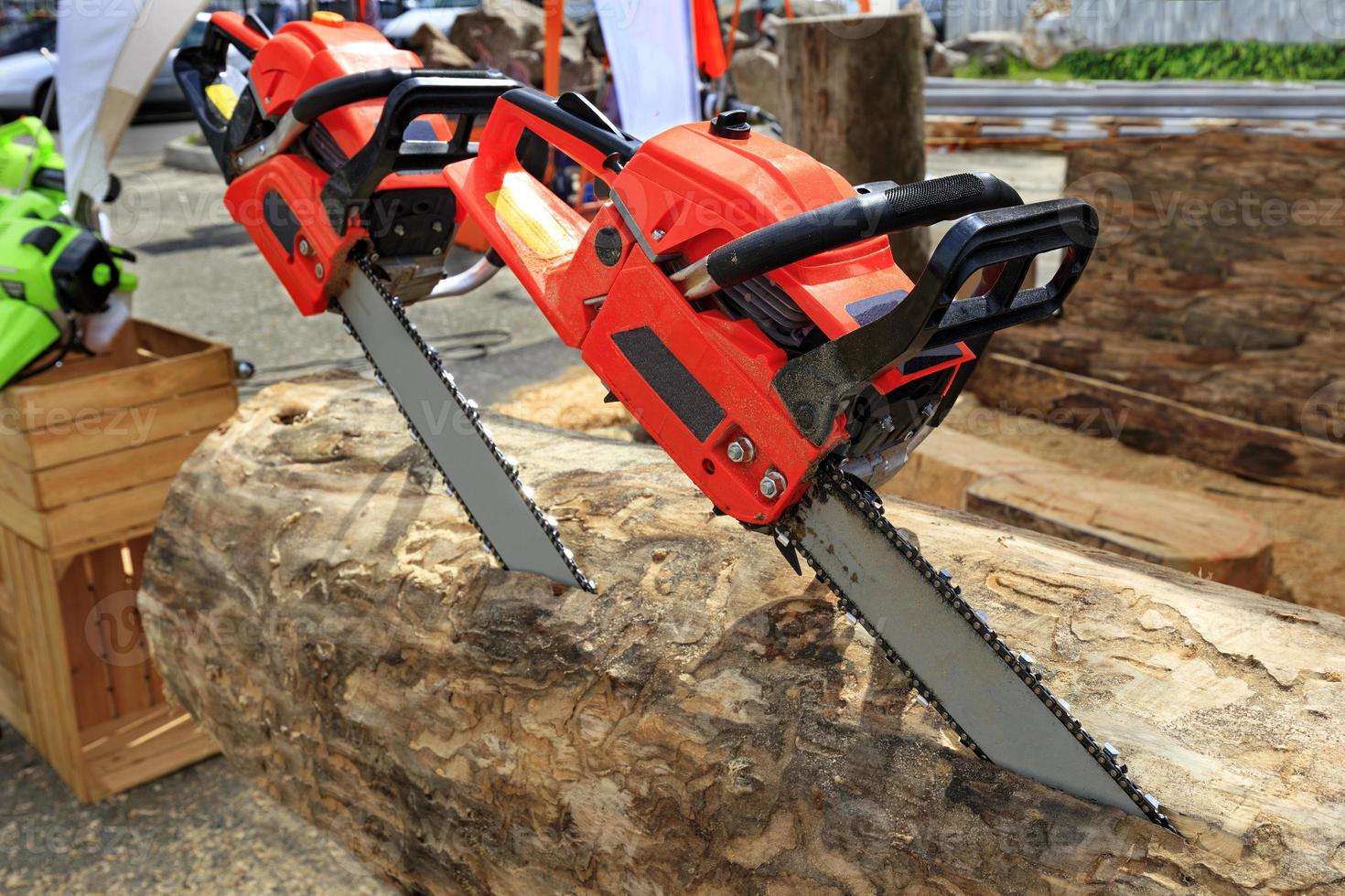 les tronçonneuses rouges sont enfoncées dans la bûche. le concept de récolte de bois. photo