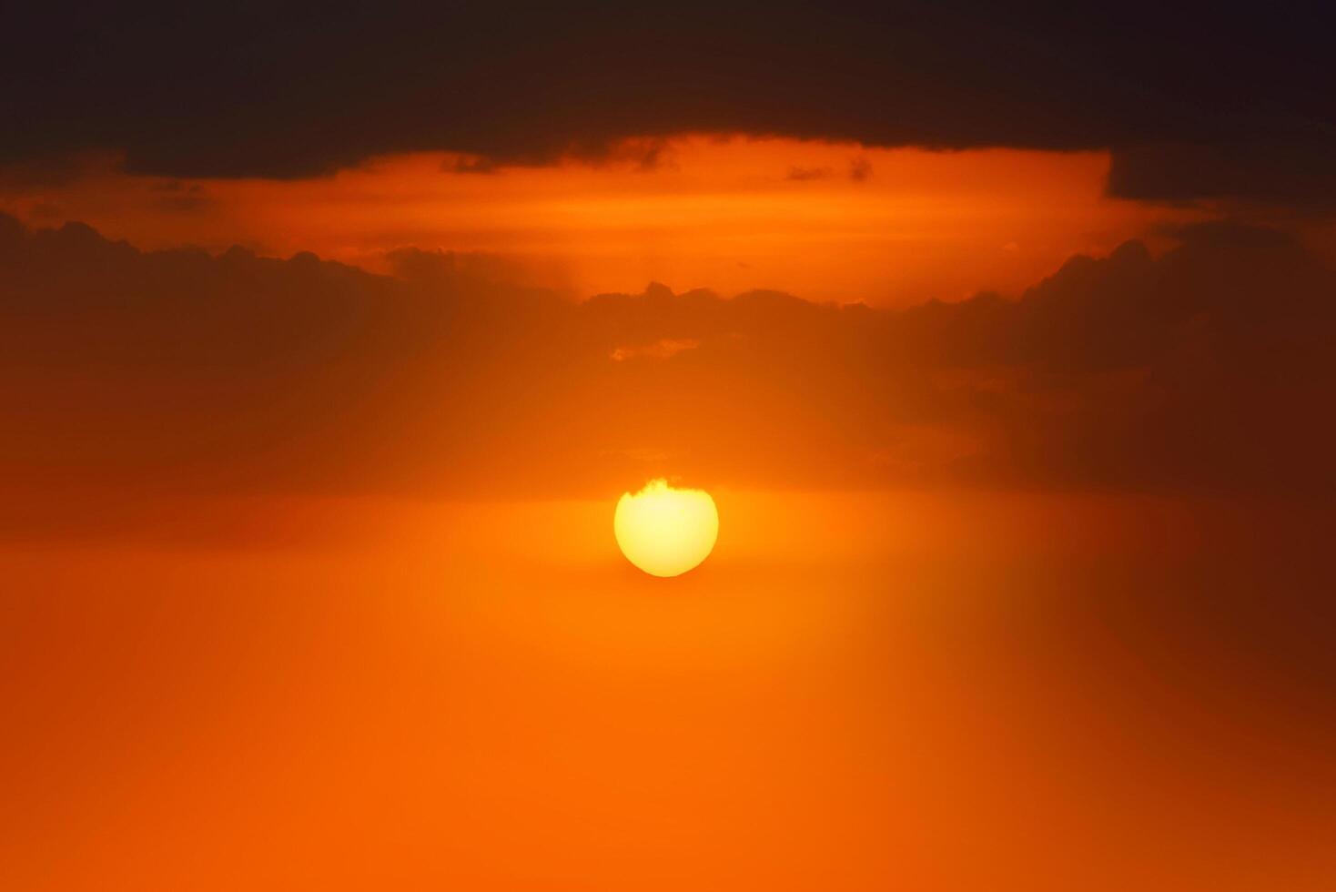 coucher de soleil orange brillant et lever de soleil magnifique sur des nuages noirs et gris avec un soleil orange vif par une fraîche matinée de printemps. photo