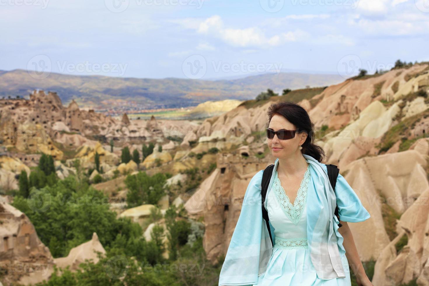 portrait d'une belle jeune femme vêtue d'une robe turquoise sur fond de paysage flou de vallées montagneuses et de canyons de cappadoce photo