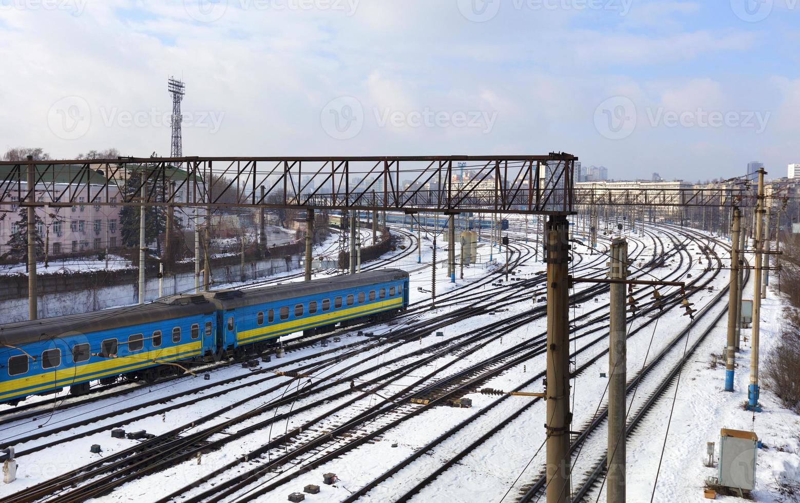 les wagons de chemin de fer de passagers roulent le long des voies ferrées en hiver dans le contexte du paysage urbain photo