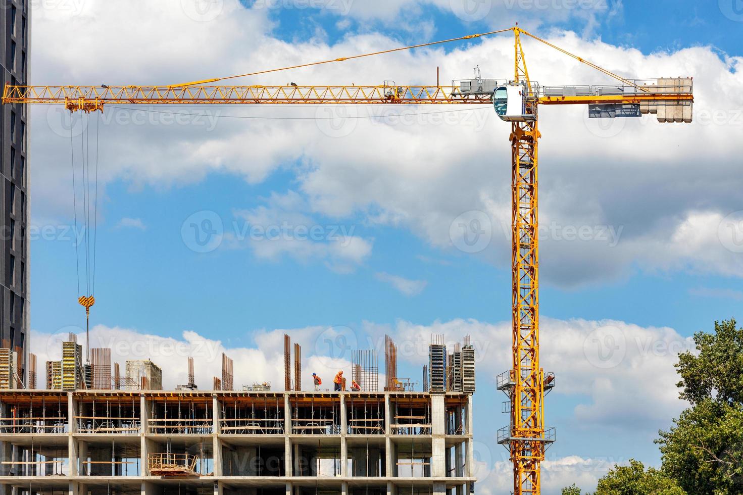 construction d'un immeuble résidentiel à plusieurs étages à l'aide d'une grue à tour contre un ciel bleu nuageux. photo