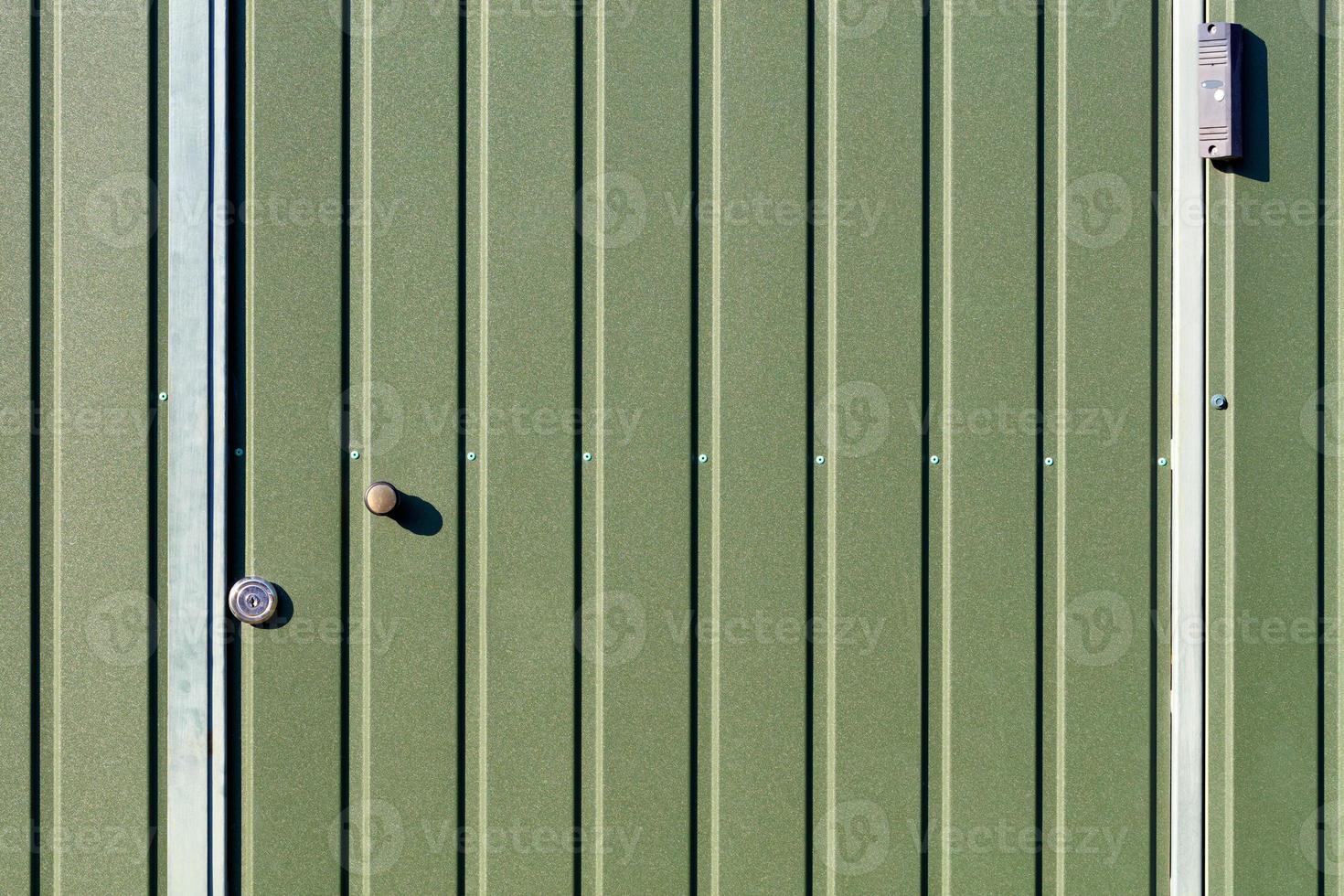 clôture métallique verte et portes en tôle d'acier ondulée avec rails verticaux et caméra de surveillance. photo