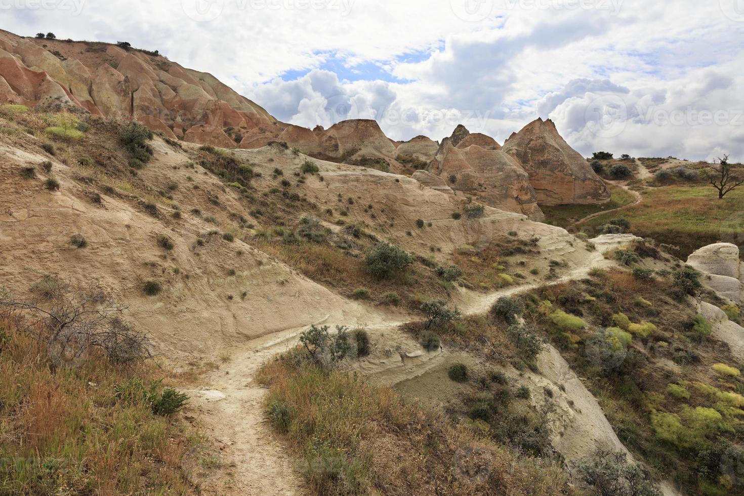 un sentier de montagne sinueux passe entre énormes et vieilles pierres dans la vallée rouge cappadocienne. photo