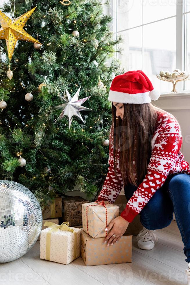 Jeune femme en pull rouge tenant une pile de cadeaux de Noël photo