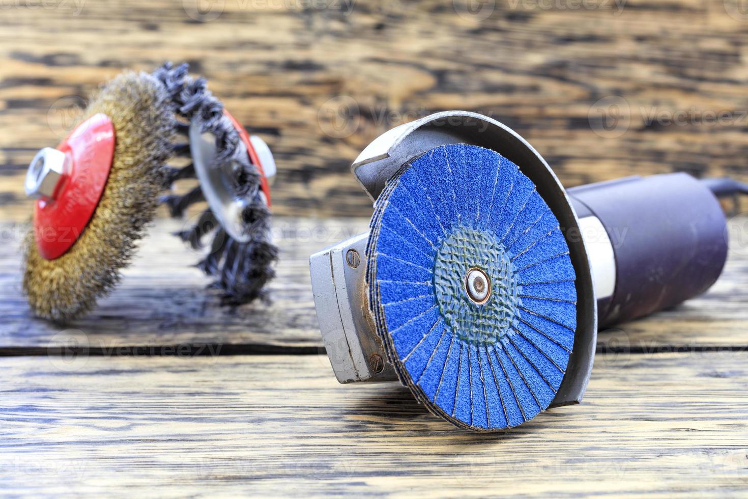 meuleuse d'angle avec brosses à disque de meulage se trouve sur le fond d'une table en bois dans un flou. photo