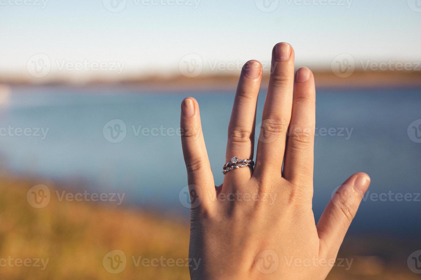 symbole de l'amour bien en vue sur la main de la jeune femme. rivière et herbes d'automne en arrière-plan. ciel bleu ensoleillé présent à l'horizon. photo