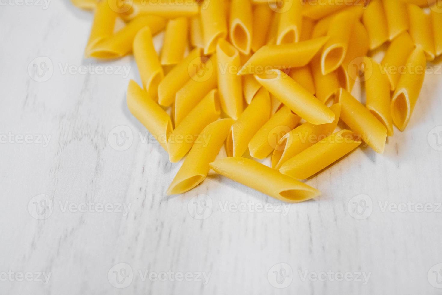 Pâtes penne rigate sur fond de table en bois blanc photo