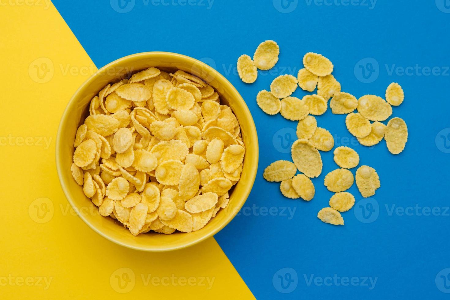 cornflakes dans un bol jaune sur fond jaune et bleu photo