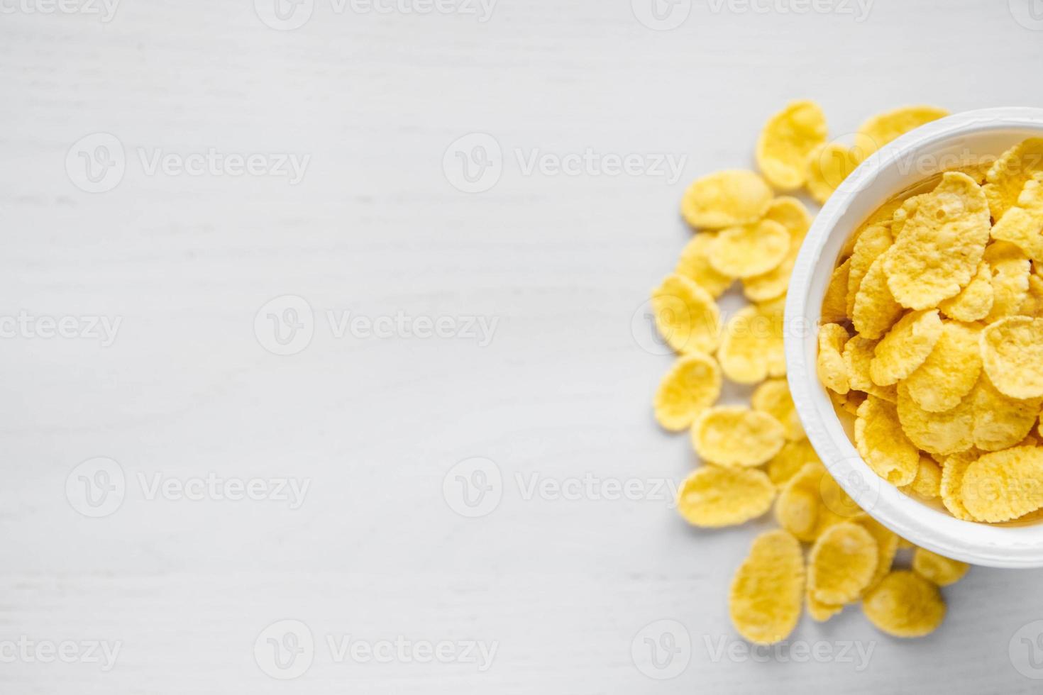 Cornflakes dans un bol blanc sur fond de bois blanc photo