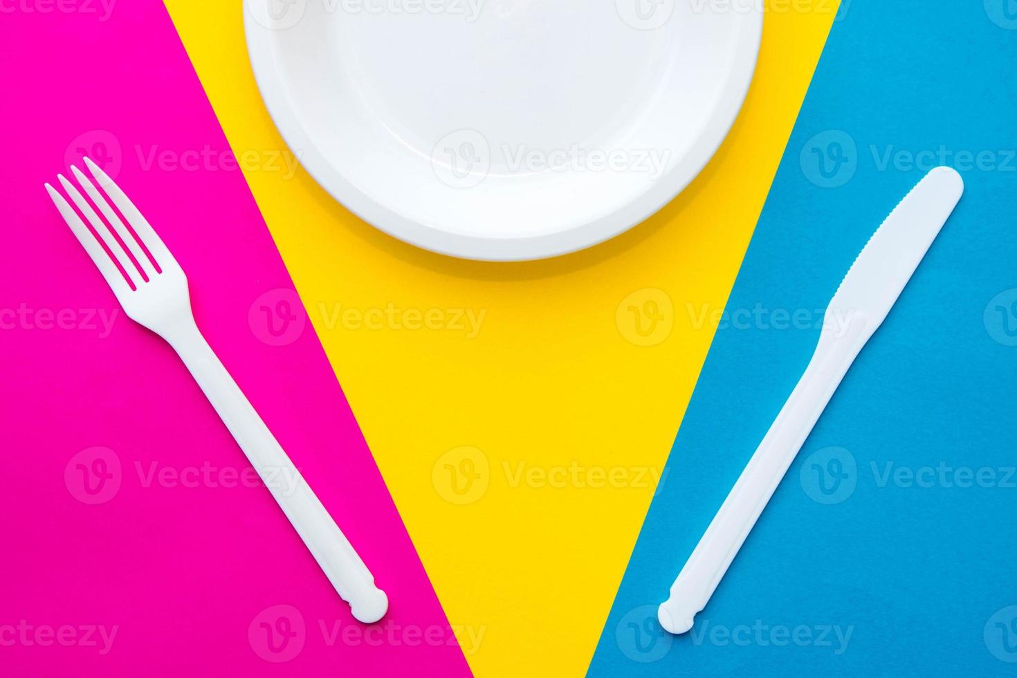 fourchette, couteau et assiette en plastique blanc sur fond multicolore photo