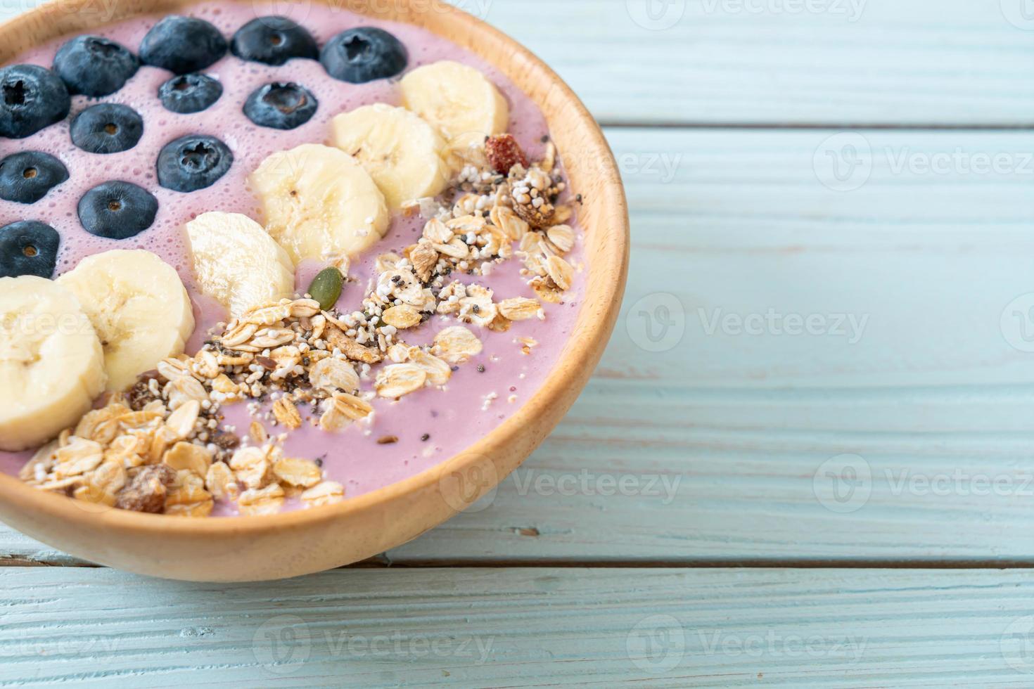 bol de smoothie au yaourt ou au yaourt avec baies bleues, banane et granola photo