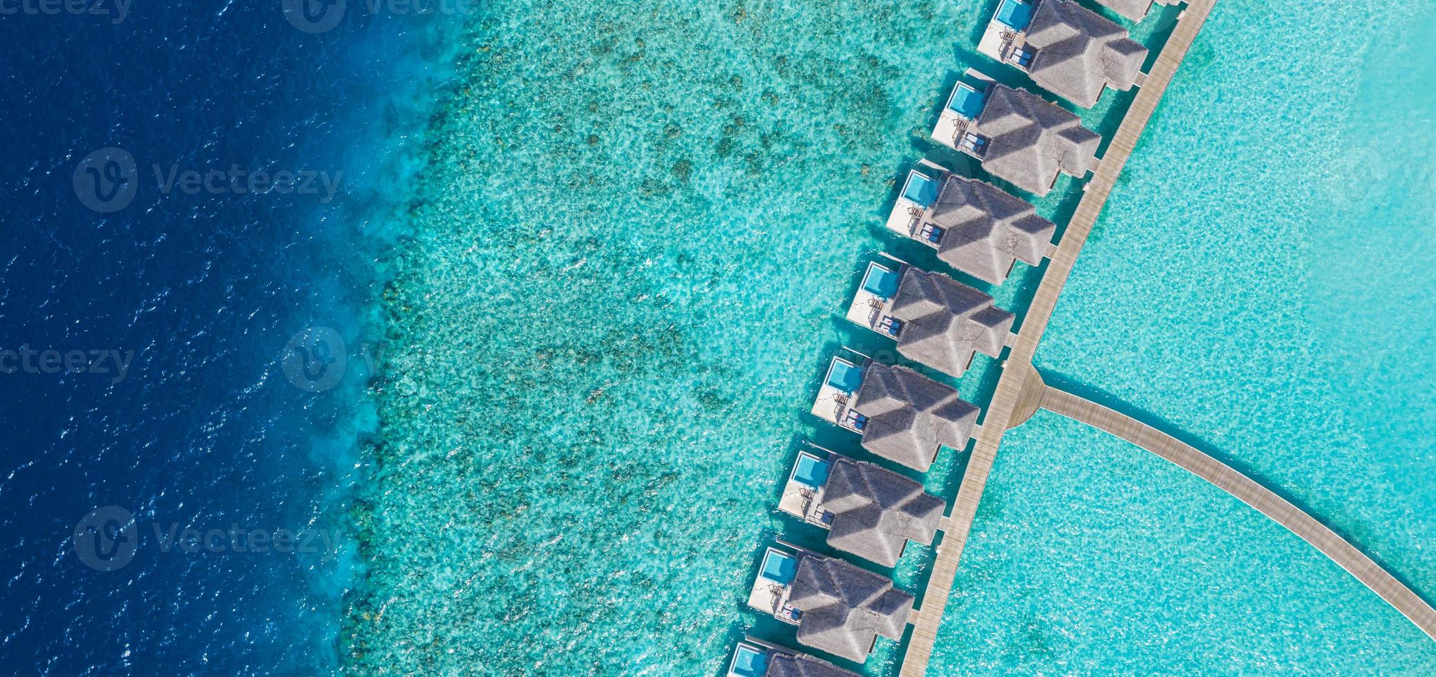 vue aérienne de l'île des maldives, complexe de villas sur l'eau de luxe et jetée en bois. ciel magnifique et plage de lagon océanique. vacances d'été vacances et concept de voyage. paradis paysage aérien panorama photo