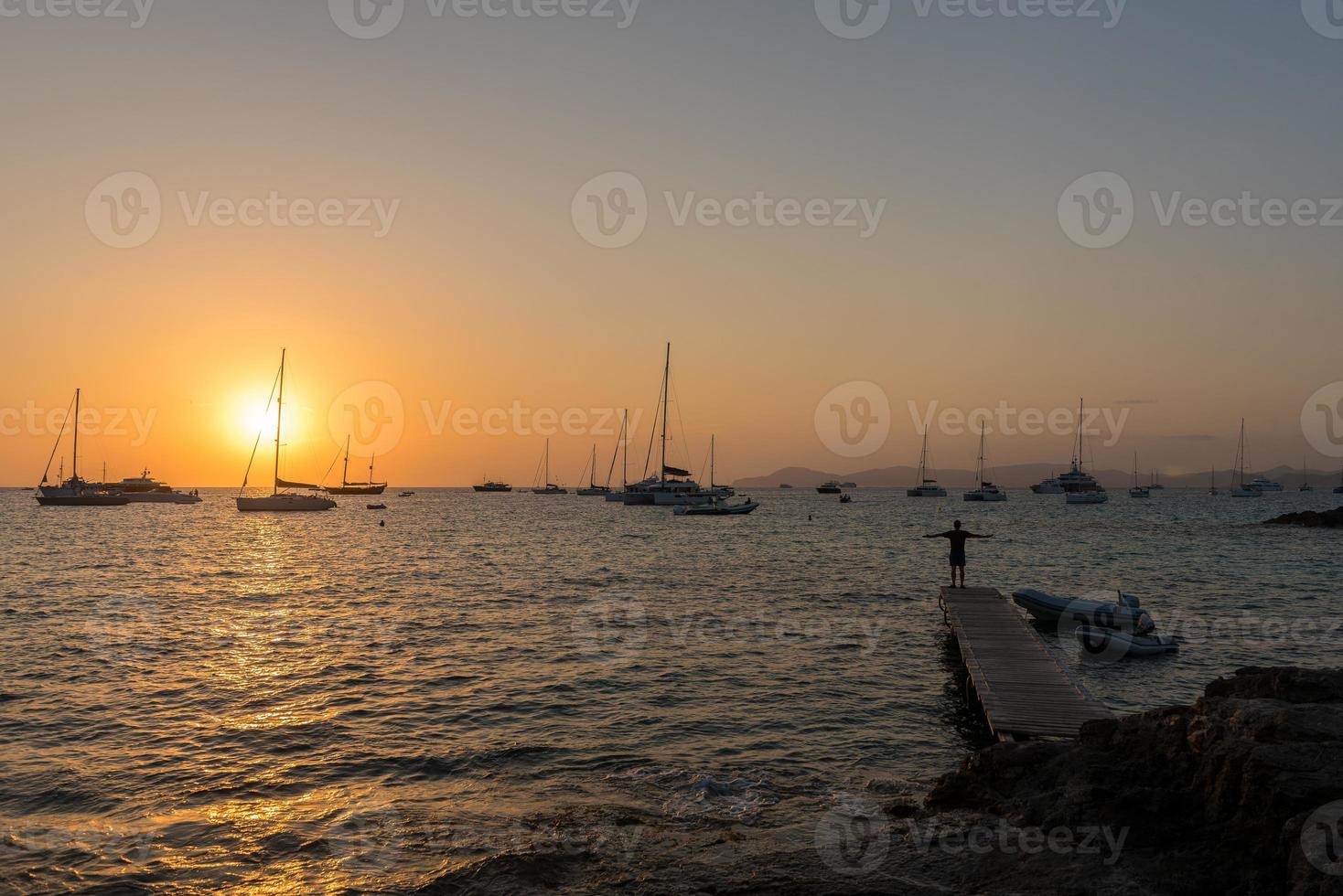 hommes dans la jetée au coucher du soleil sur la plage de ses illietes sur l'île de formentera à l'été 2021 photo