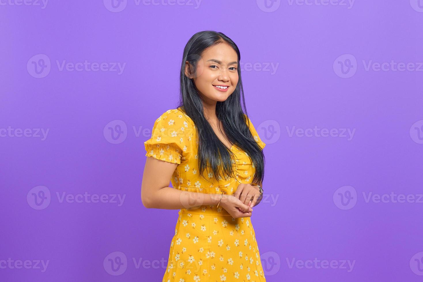 souriante jeune femme asiatique garde la main ensemble et se sent optimiste sur fond violet photo