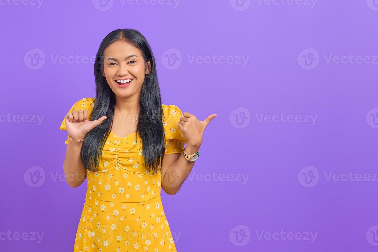 Portrait de jeune femme asiatique souriante pointant le pouce sur l'espace de copie sur fond violet photo