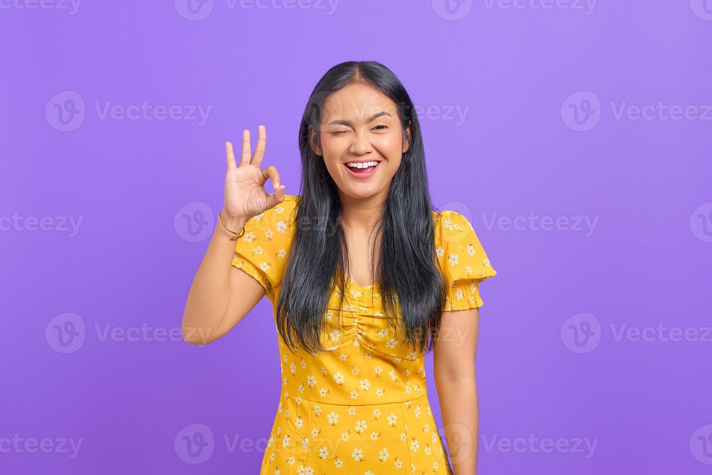 joyeuse jeune femme asiatique fait un geste correct, démontre un symbole d'approbation sur fond violet photo