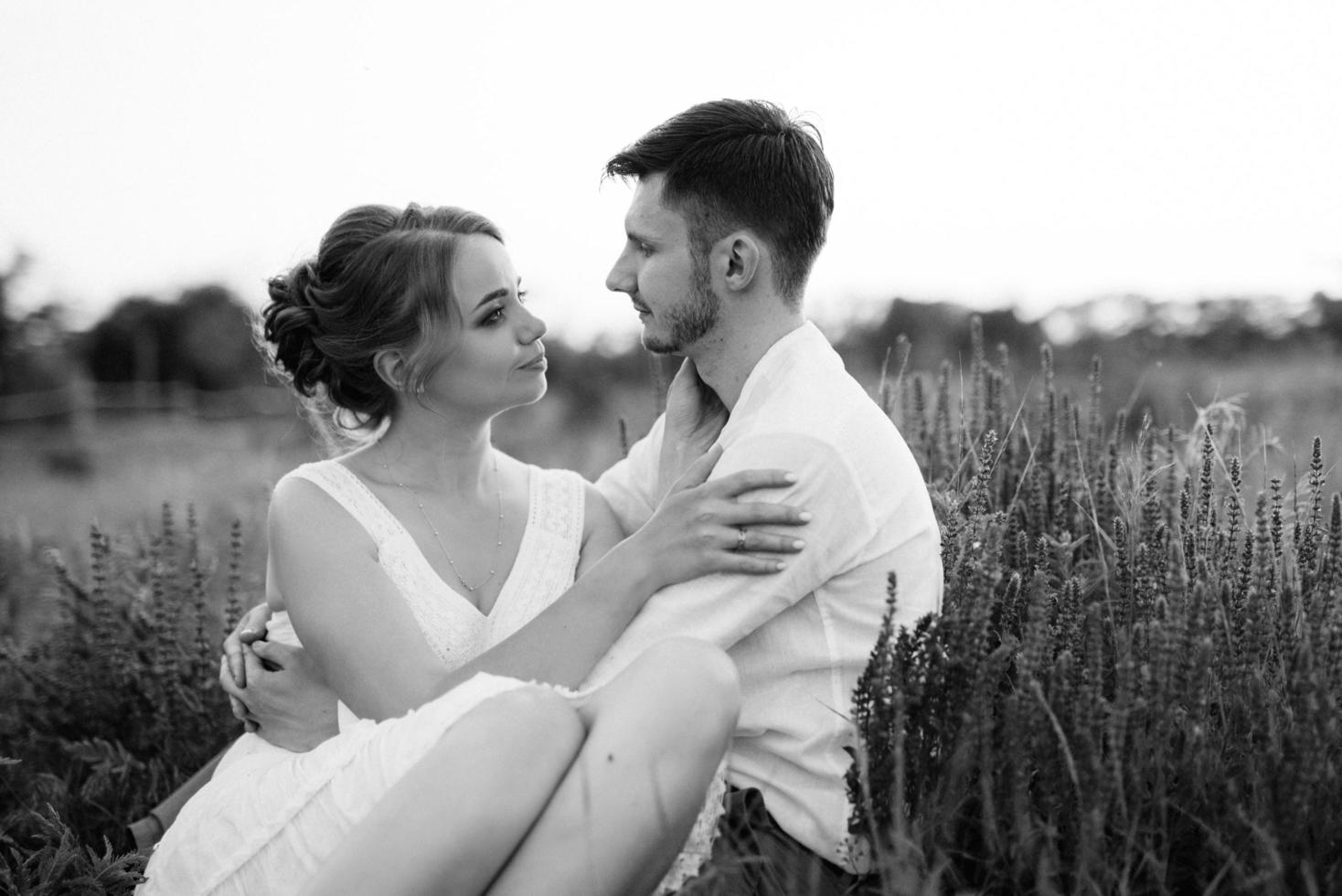 fille dans une robe d'été blanche et un gars dans une chemise blanche sur une promenade au coucher du soleil avec un bouquet photo