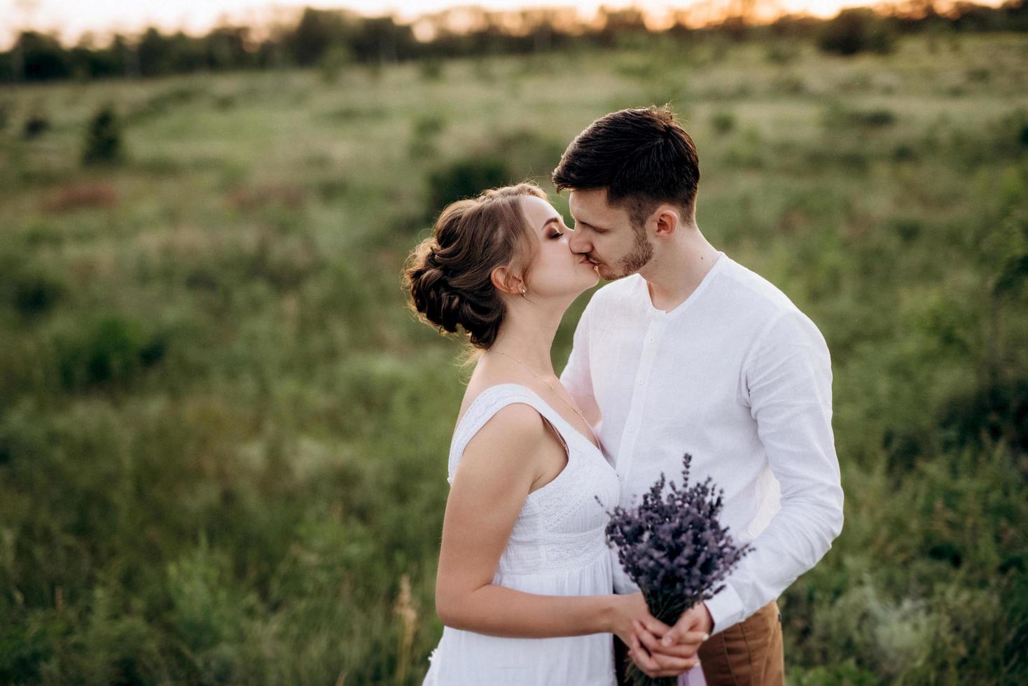 fille dans une robe d'été blanche et un gars dans une chemise blanche sur une promenade au coucher du soleil avec un bouquet photo