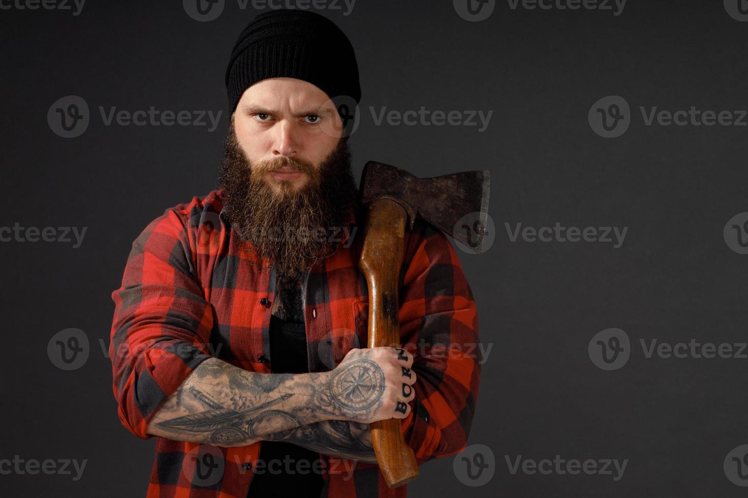 bel homme aux cheveux longs avec une hache dans les mains sur un fond de studio sombre photo