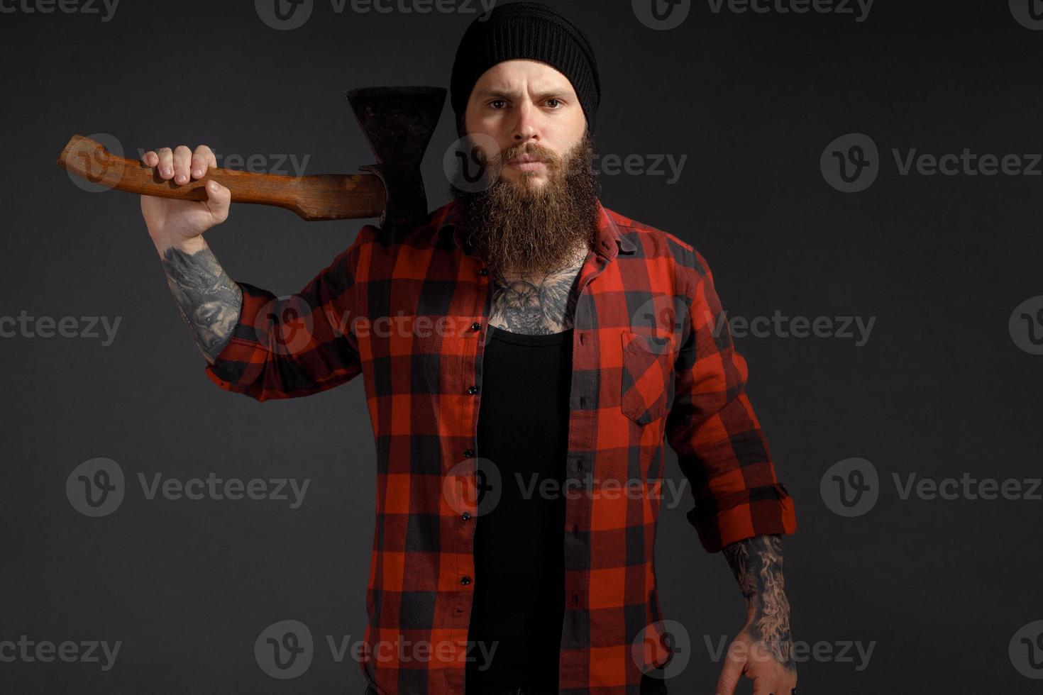 bel homme aux cheveux longs avec une hache dans les mains sur un fond de studio sombre photo