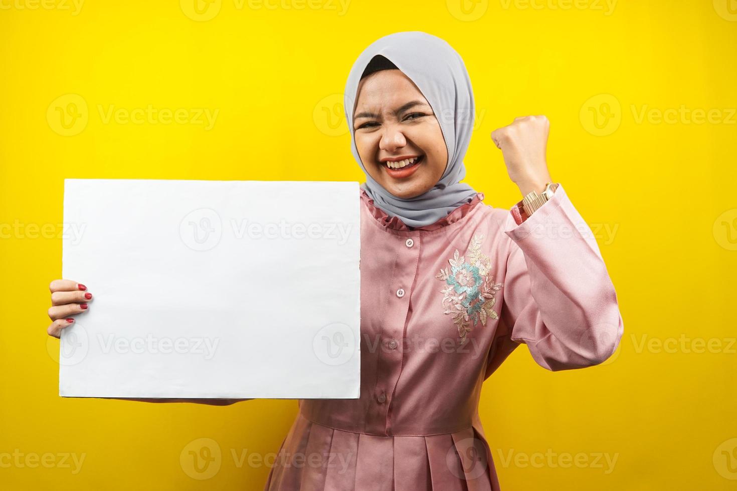 jolie jeune femme musulmane joyeuse tenant une bannière vide vierge, une pancarte, un tableau blanc, un panneau vierge, un panneau publicitaire blanc, présentant quelque chose dans l'espace de copie, promotion photo