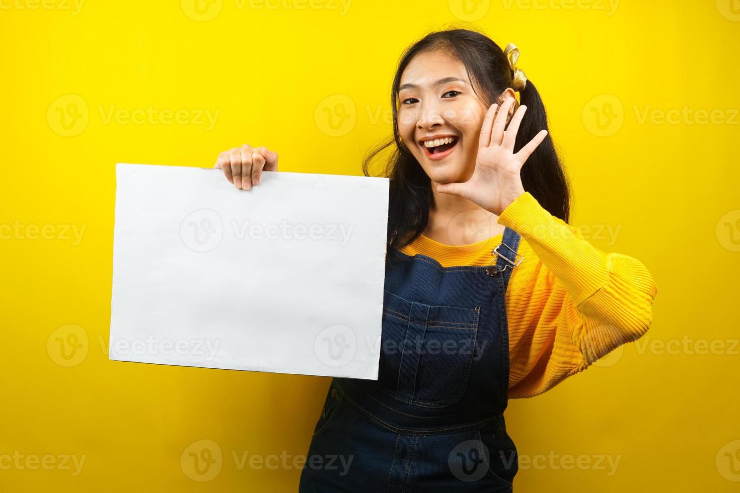 jolie et mignonne jeune femme joyeuse tenant une bannière vide vierge, une pancarte, un tableau blanc, un panneau vierge, un panneau publicitaire blanc, présentant quelque chose dans l'espace de copie, promotion photo