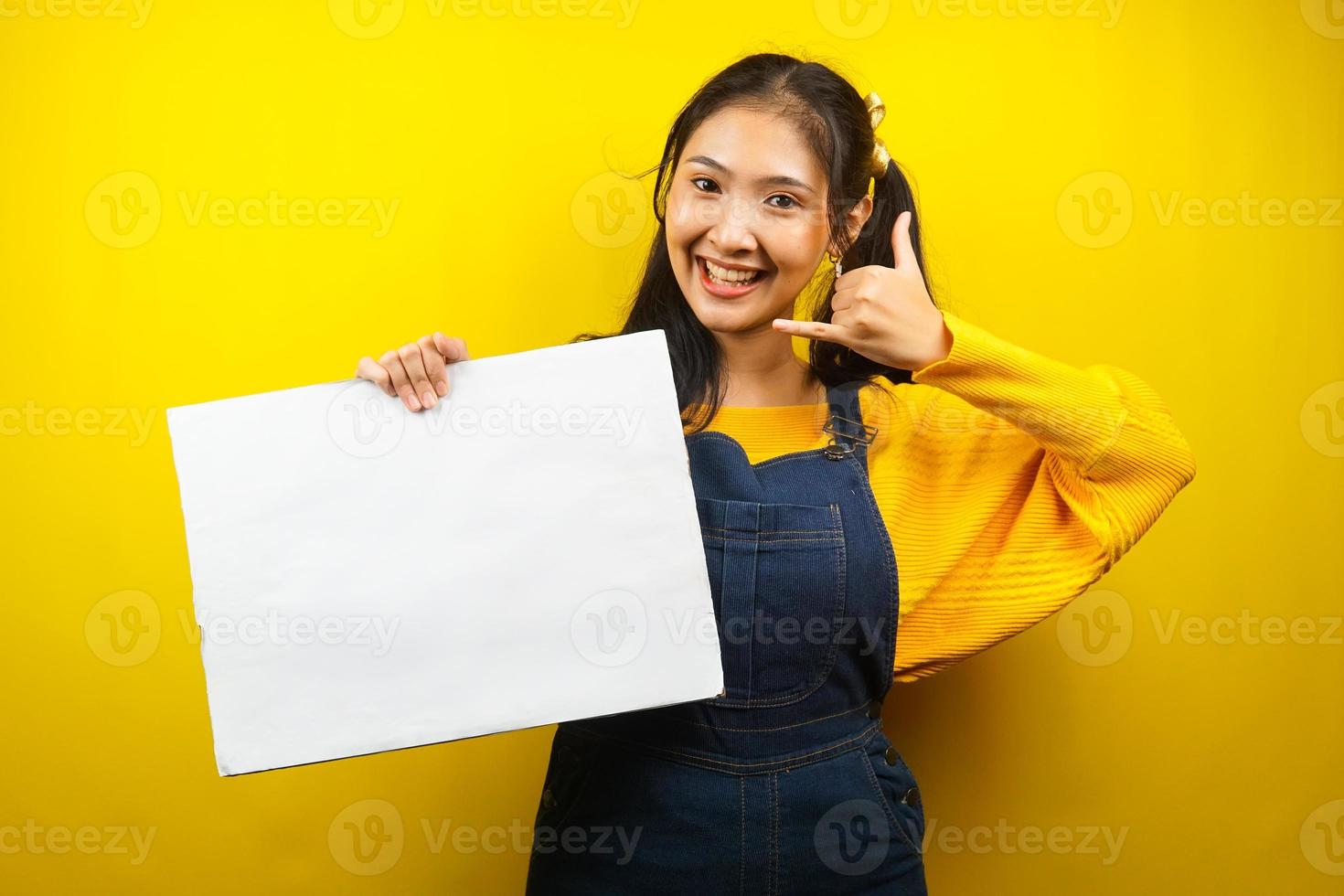 jolie et mignonne jeune femme joyeuse tenant une bannière vide vierge, une pancarte, un tableau blanc, un panneau vierge, un panneau publicitaire blanc, présentant quelque chose dans l'espace de copie, promotion photo