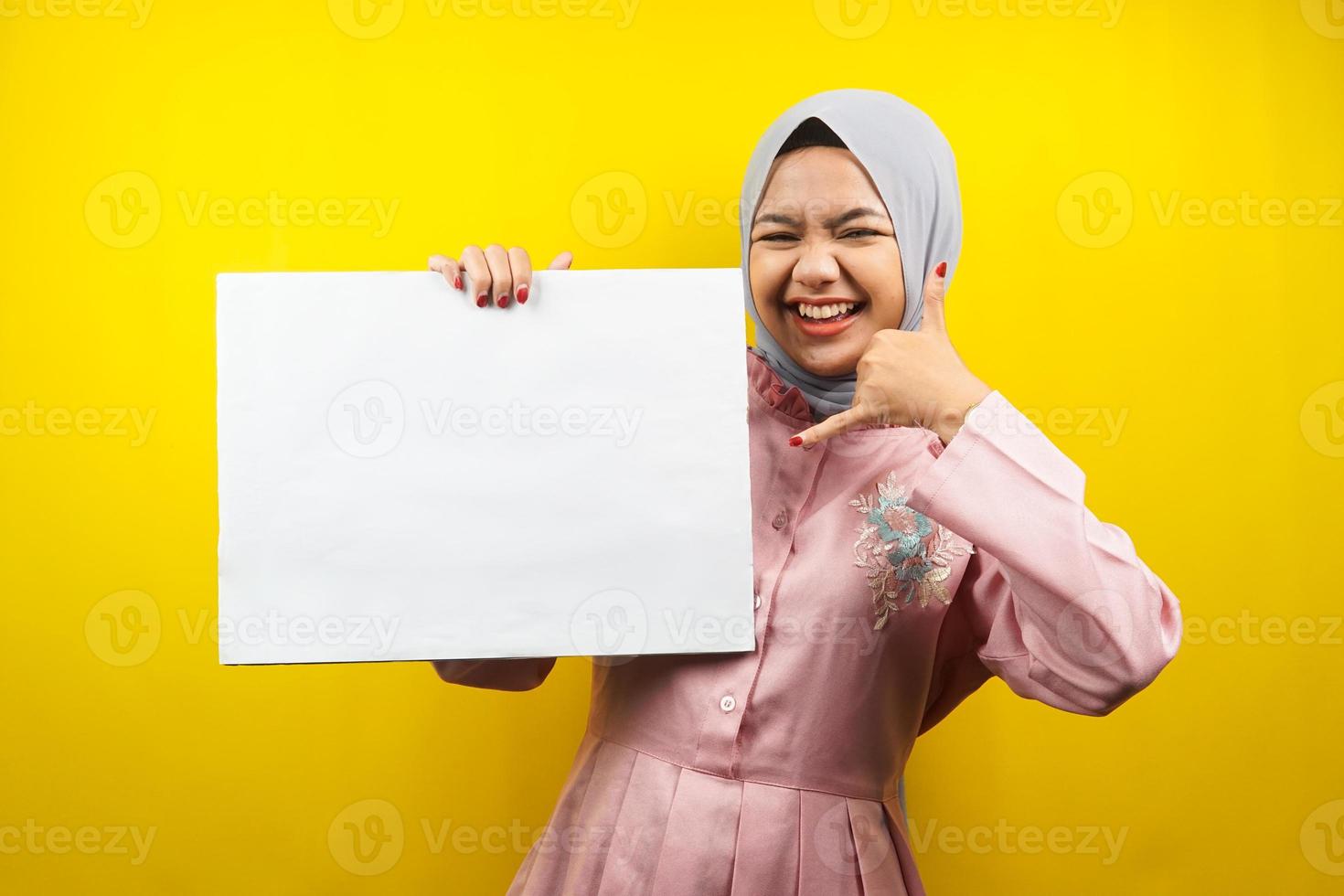 jolie jeune femme musulmane joyeuse tenant une bannière vide vierge, une pancarte, un tableau blanc, un panneau vierge, un panneau publicitaire blanc, présentant quelque chose dans l'espace de copie, promotion photo