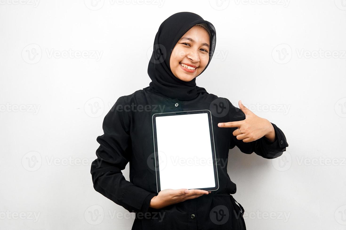 belle jeune femme musulmane asiatique souriante, tenant une tablette à la main avec un écran blanc ou blanc, faisant la promotion de l'application, faisant la promotion du produit, présentant quelque chose, excité et joyeux, isolé sur fond blanc photo