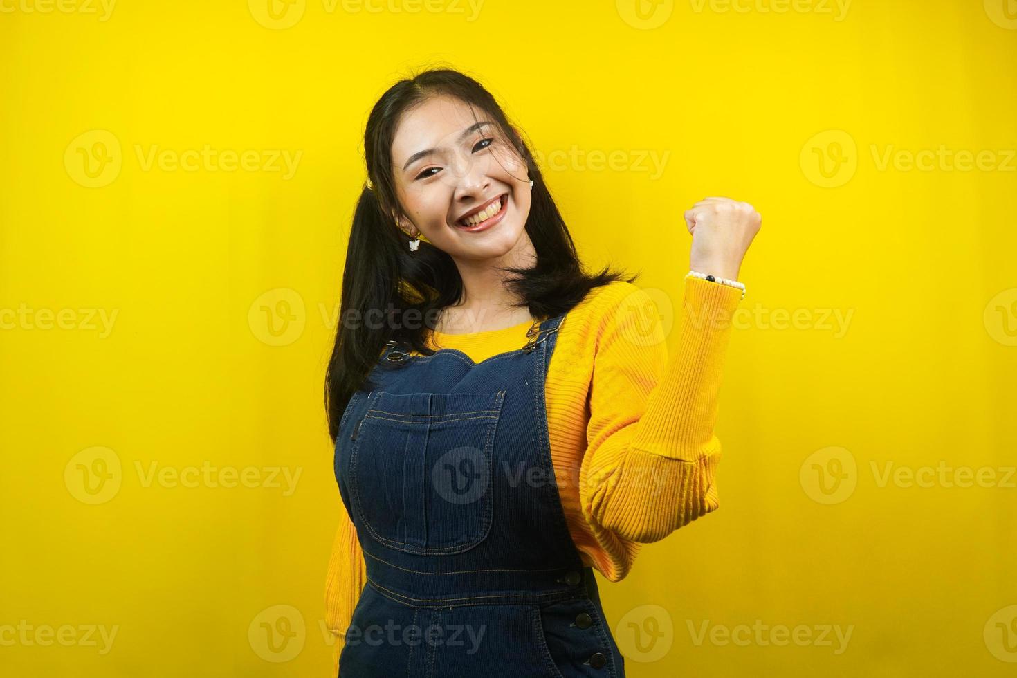 jolie et mignonne jeune femme joyeuse, confiante, les poings fermés, succès, bon travail, victoire, isolée photo