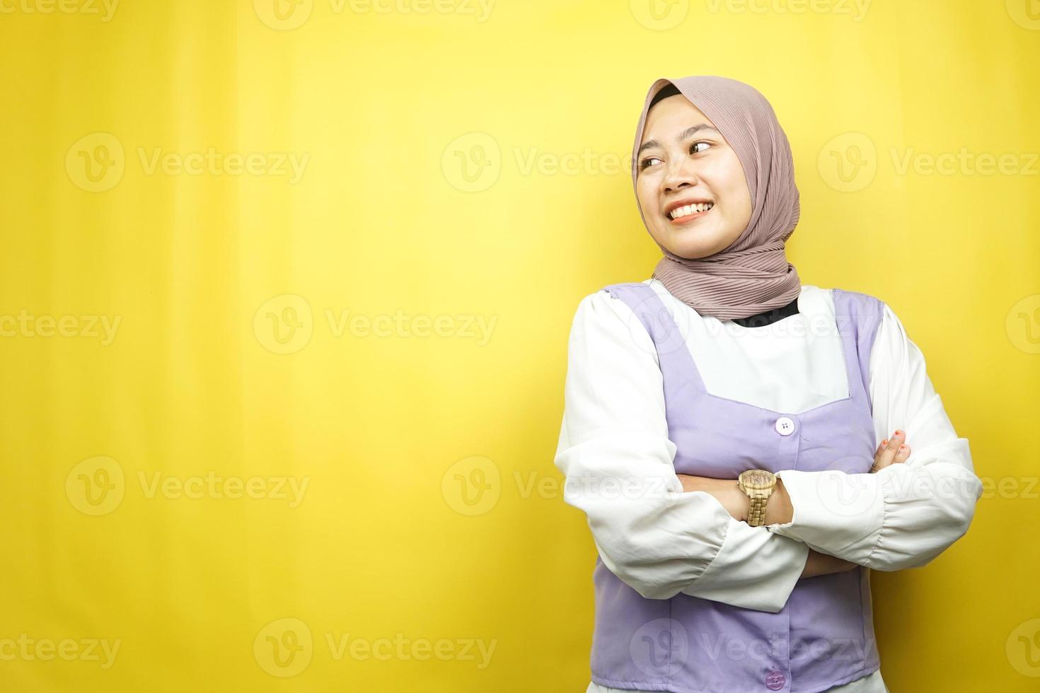 belle jeune femme musulmane asiatique confiante et gaie à la recherche d'un espace vide présentant quelque chose, isolé sur fond jaune photo