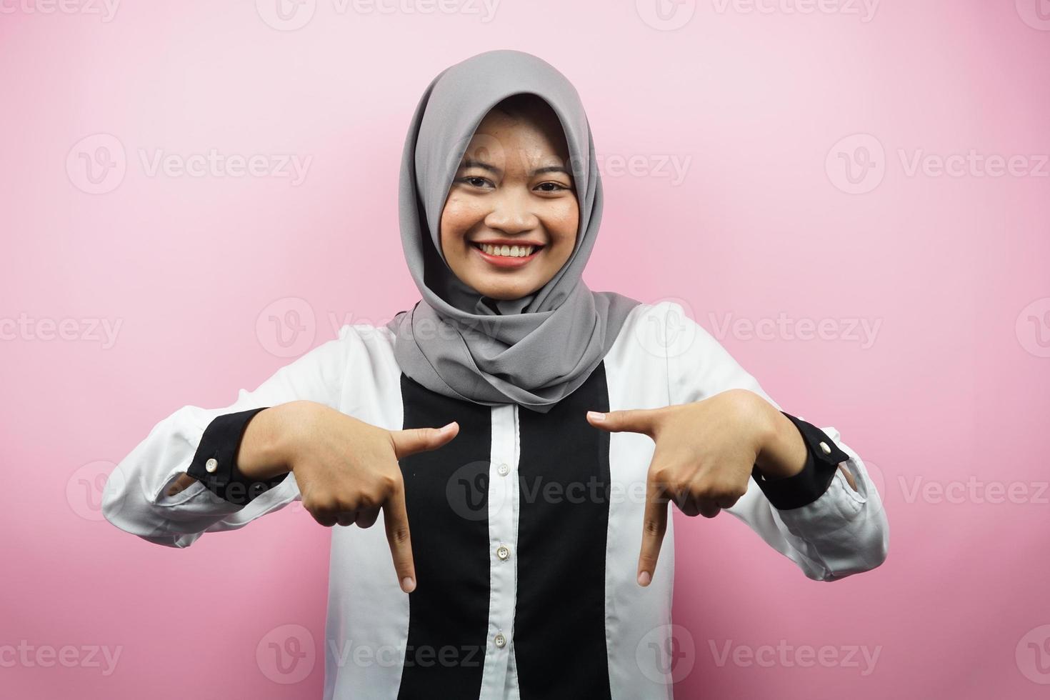 belle jeune femme musulmane asiatique avec les mains pointées vers le bas, les mains cliquez sur le lien ci-dessous, les mains présentant quelque chose, isolées sur fond rose photo