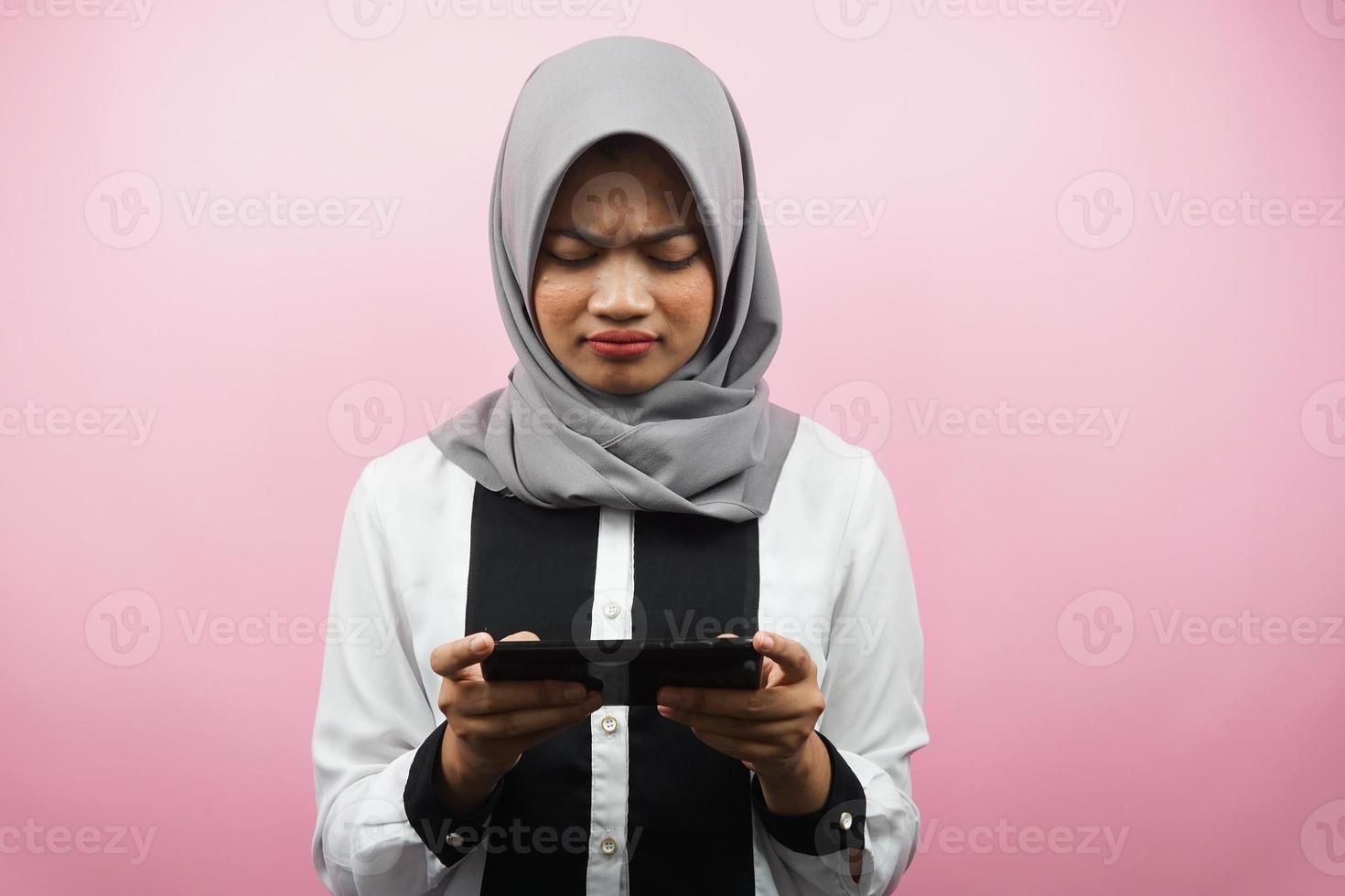 belle jeune femme musulmane asiatique avec une main tenant un smartphone, jouant au jeu, triste, défaite, malheureuse, isolée sur fond rose, concept publicitaire photo