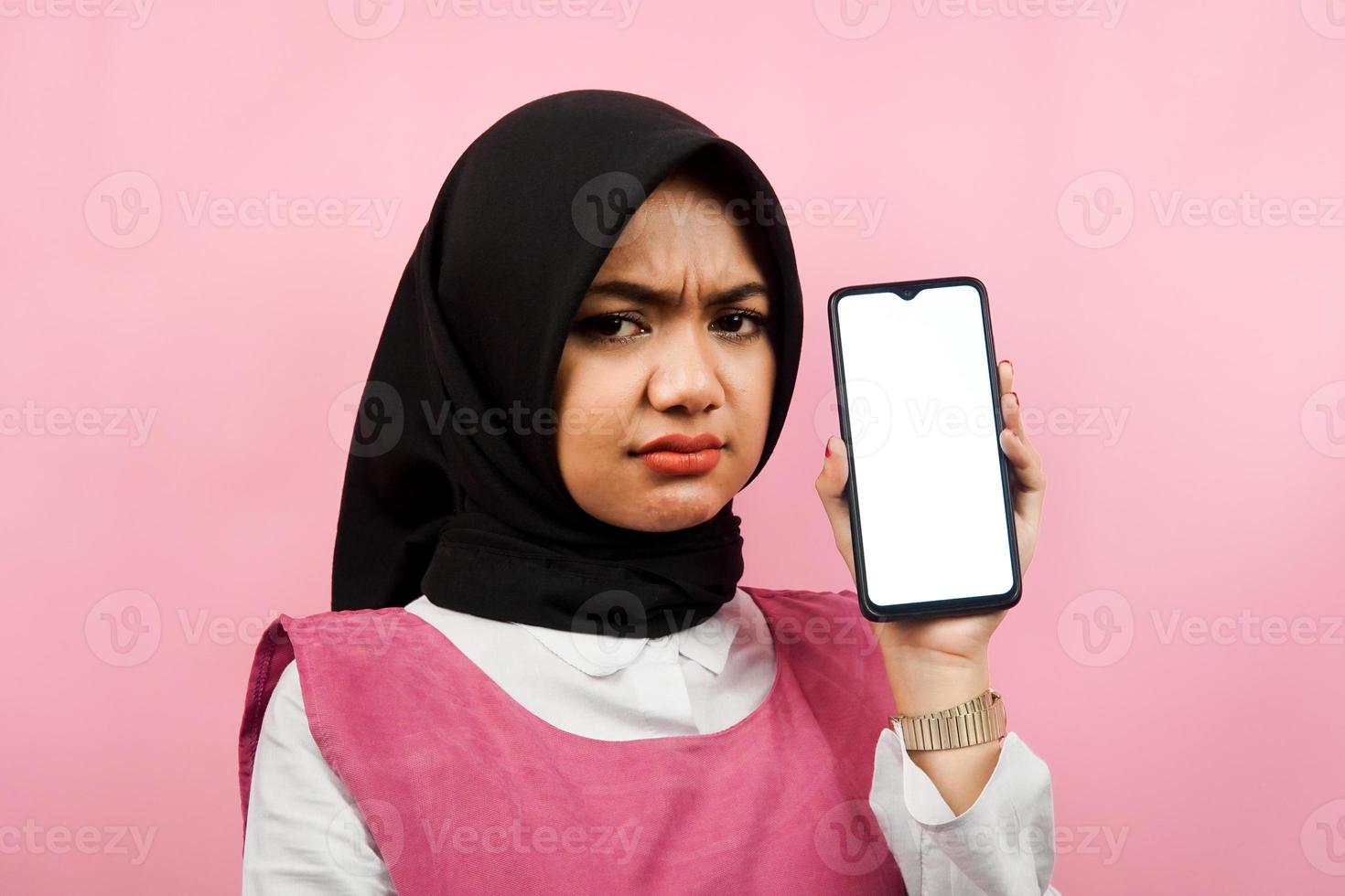 gros plan d'une jeune femme musulmane belle et joyeuse tenant un smartphone avec écran blanc ou vierge, faisant la promotion de l'application, faisant la promotion de quelque chose, isolé, concept publicitaire photo