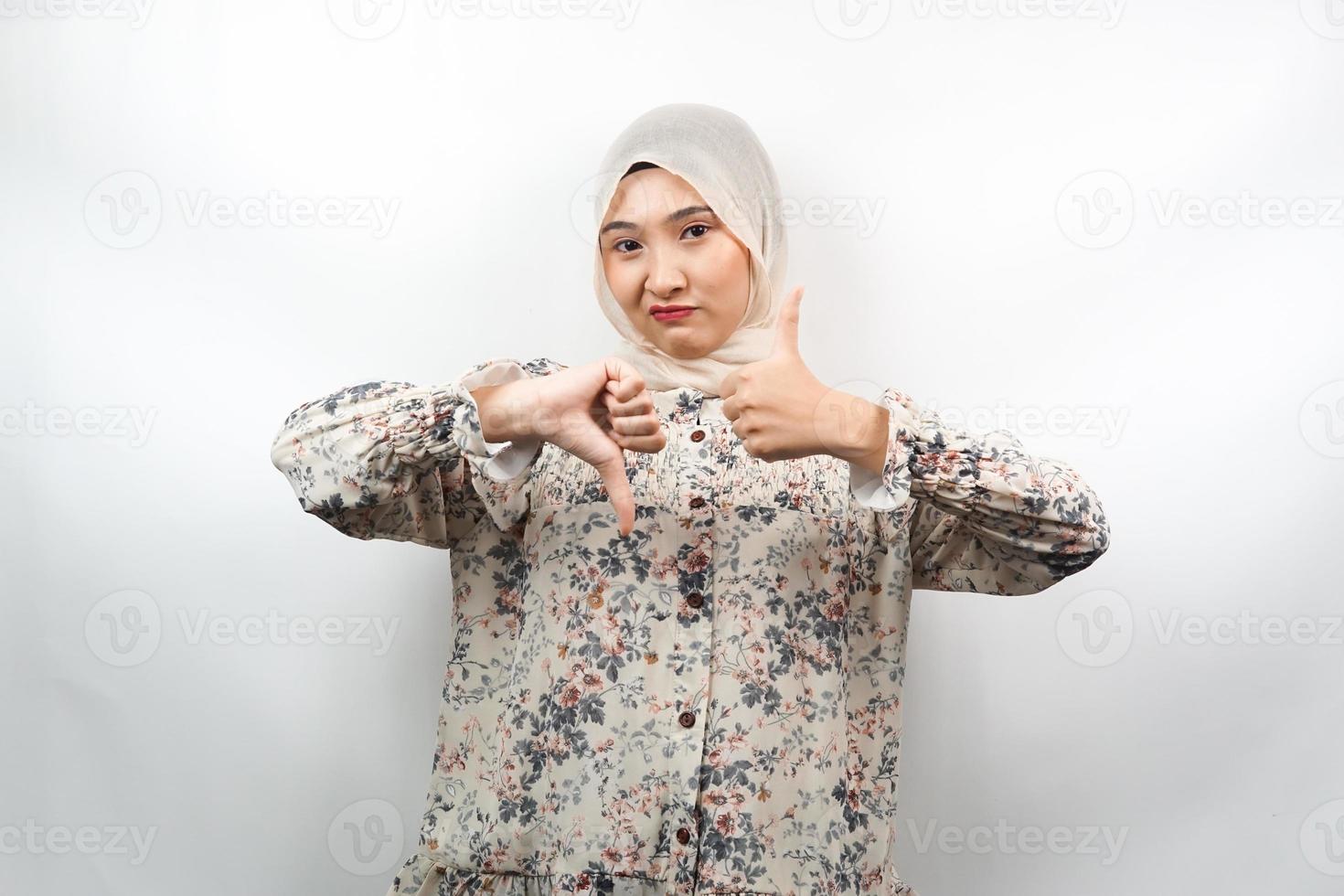 belle jeune femme musulmane asiatique avec signe de la main aime ou n'aime pas, oui ou non, heureuse ou triste, comparant deux choses, isolées sur fond blanc photo