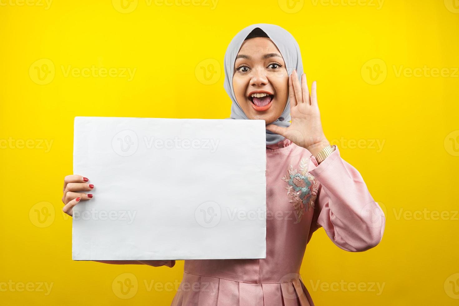 jolie jeune femme musulmane joyeuse tenant une bannière vide vierge, une pancarte, un tableau blanc, un panneau vierge, un panneau publicitaire blanc, présentant quelque chose dans l'espace de copie, promotion photo