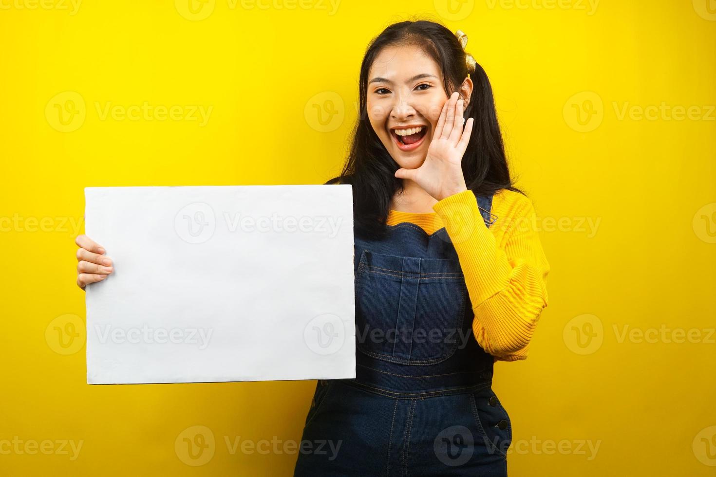 jolie et mignonne jeune femme joyeuse tenant une bannière vide vierge, une pancarte, un tableau blanc, un panneau vierge, un panneau publicitaire blanc, présentant quelque chose dans l'espace de copie, promotion photo