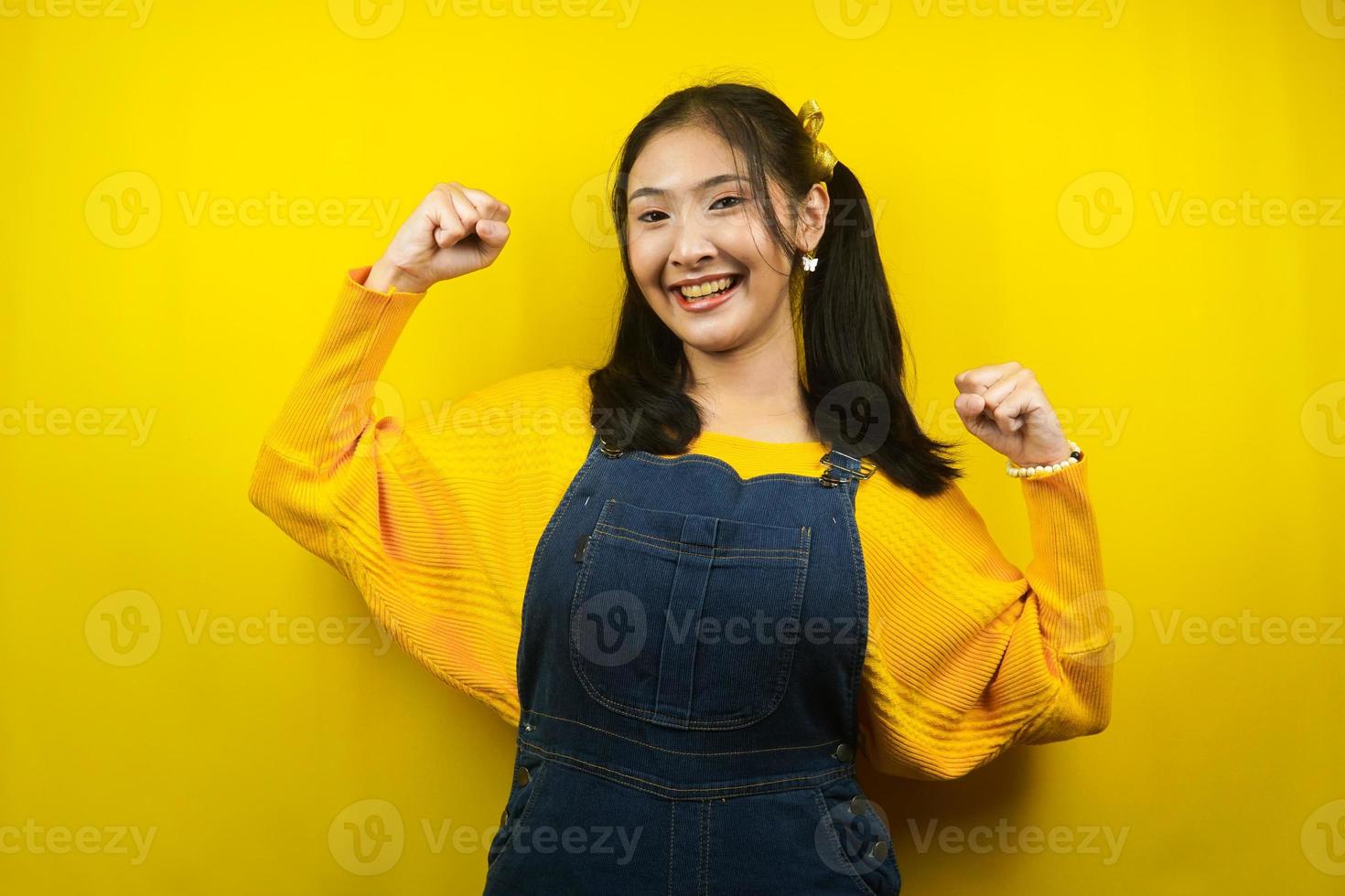 jolie et mignonne jeune femme joyeuse, confiante, les poings fermés, succès, bon travail, victoire, isolée photo