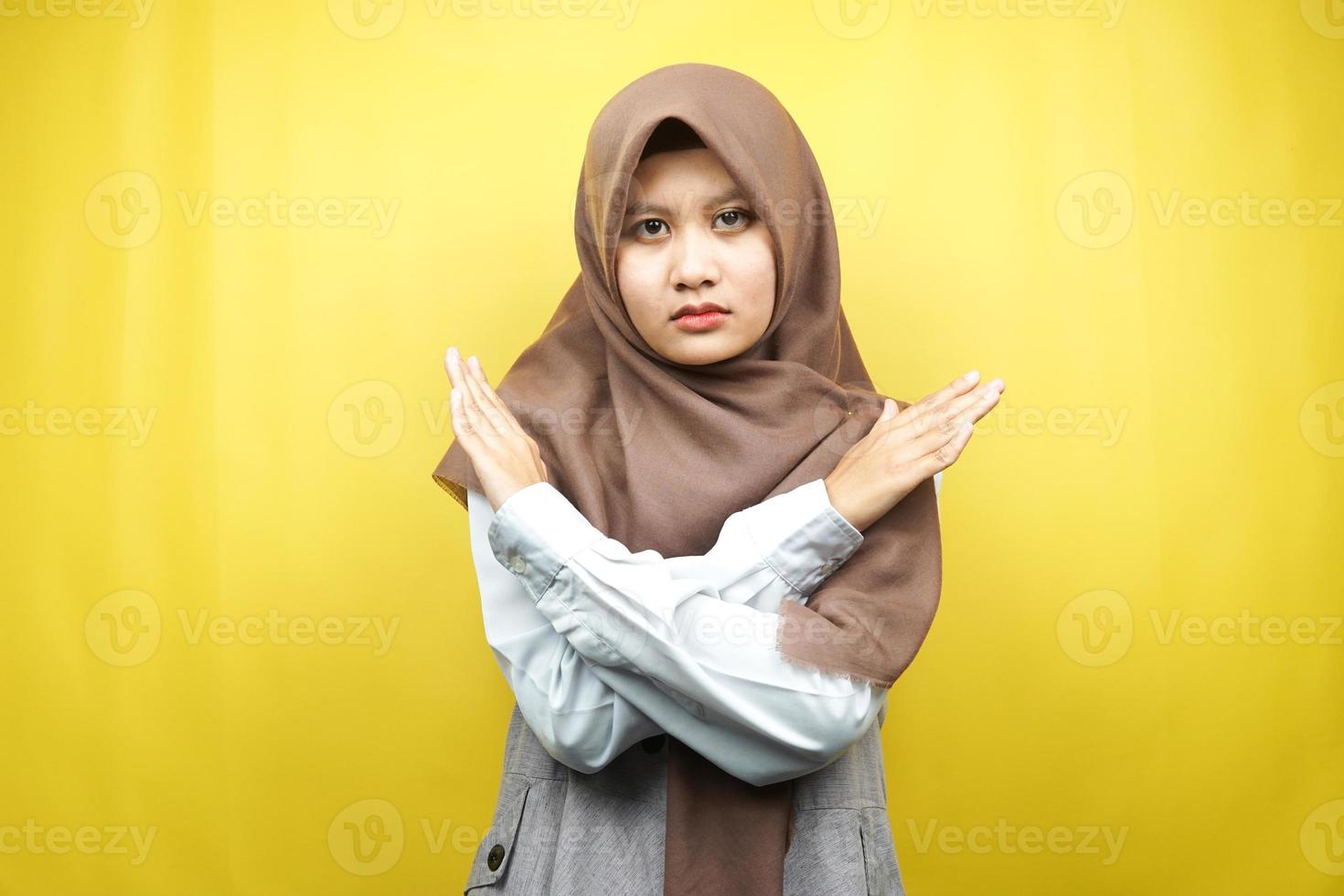 belle jeune femme musulmane asiatique aux bras croisés, mains montrant le refus, mains montrant l'interdiction, mains montrant la désapprobation, isolées sur fond jaune photo