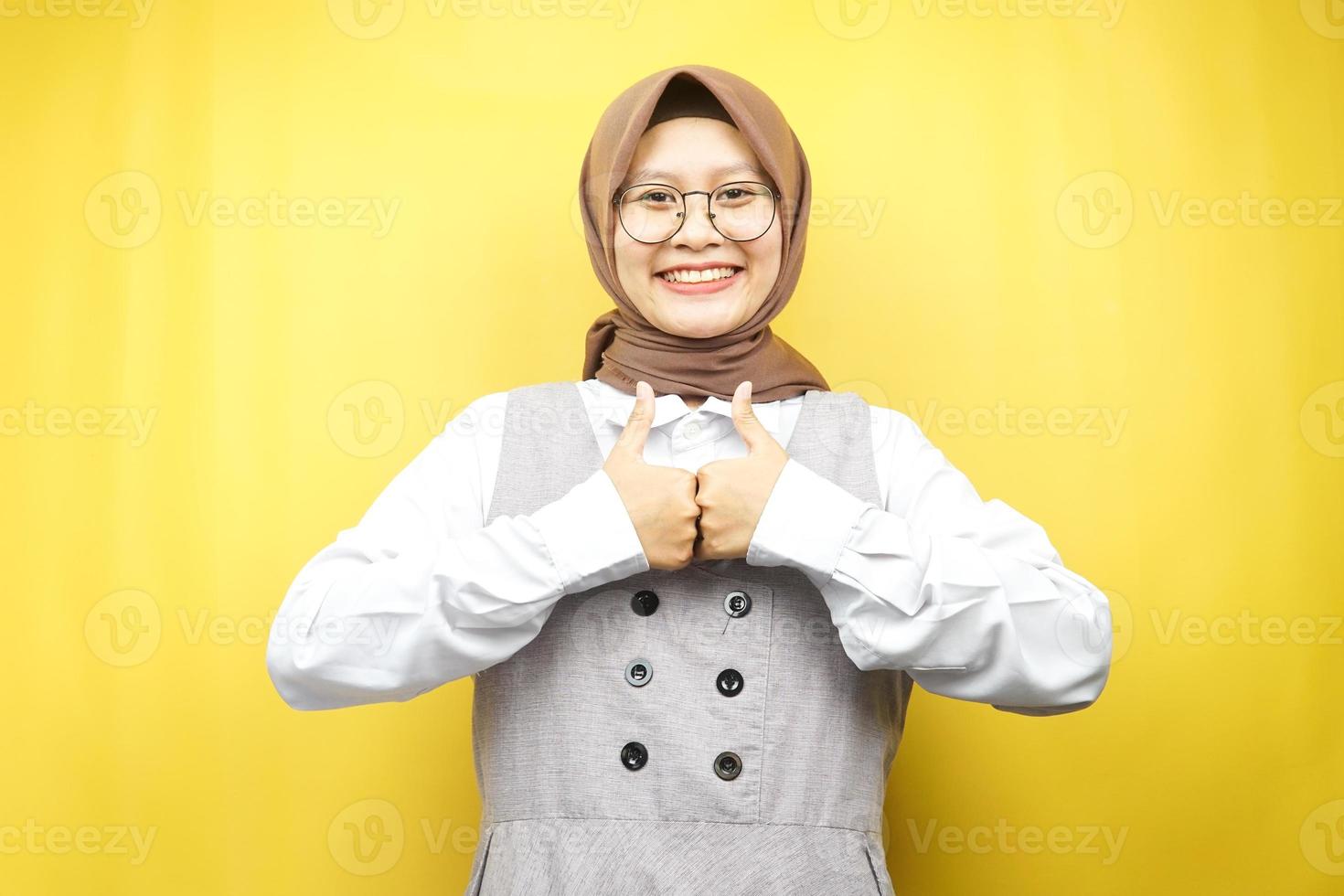 belle jeune femme musulmane asiatique avec les mains en l'air, signe ok, bon travail, succès, victoire, souriante confiante, enthousiaste et joyeuse, regardant la caméra isolée sur fond jaune photo