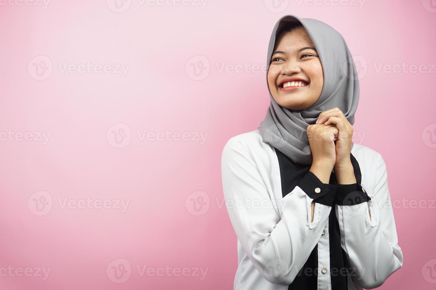 belle jeune femme musulmane asiatique confiante et gaie à la recherche d'un espace vide présentant quelque chose, isolé sur fond rose photo