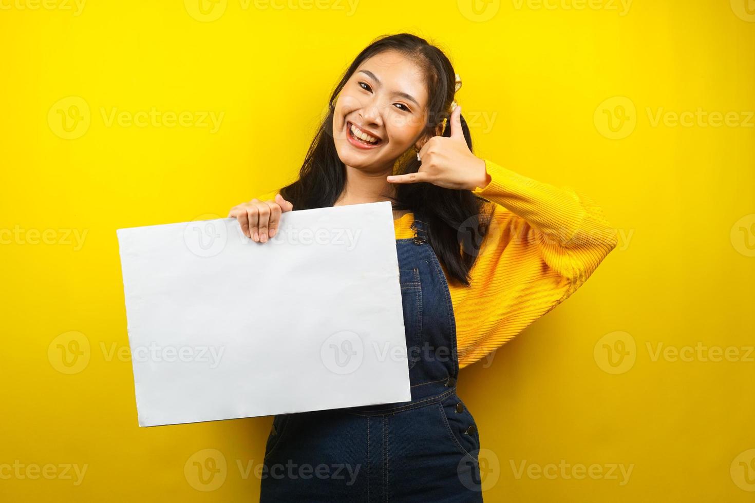 jolie et mignonne jeune femme joyeuse tenant une bannière vide vierge, une pancarte, un tableau blanc, un panneau vierge, un panneau publicitaire blanc, présentant quelque chose dans l'espace de copie, promotion photo