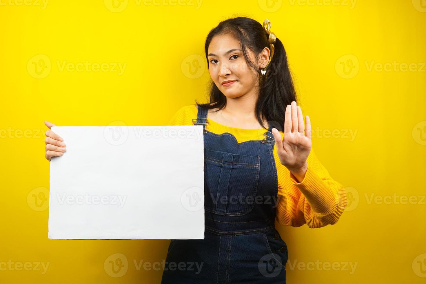 jolie et mignonne jeune femme joyeuse tenant une bannière vide vierge, une pancarte, un tableau blanc, un panneau vierge, un panneau publicitaire blanc, présentant quelque chose dans l'espace de copie, promotion photo